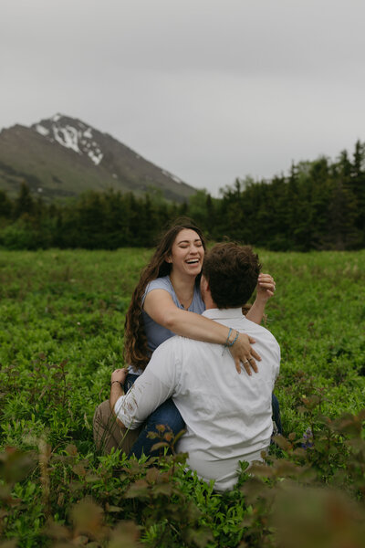 A couple sitting on one another in a field.