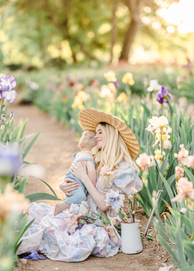An expecting mother stands in a field of poppy flowers while holding her toddler child and gently placing her nose to his cheek photographed by Bay area photographer, Light Livin Photography.