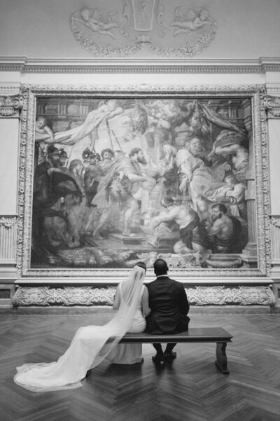 Bride and groom sitting together looking at painting