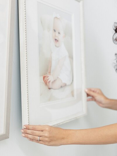 A woman is holding a framed photo of a baby taken by Charlotte portrait photographer.
