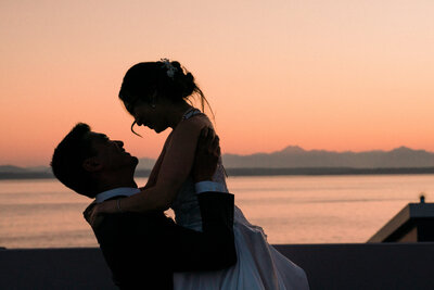 Husband kissing new wife at Seattle waterfront with love and romance all around captured by Washington wedding photographers