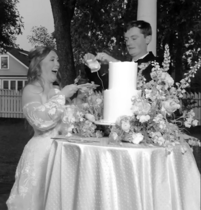 bride and groom cut their wedding cake at twilight. The cake is surrounded by garden style flowers. photograph captured by a wedding day content creator