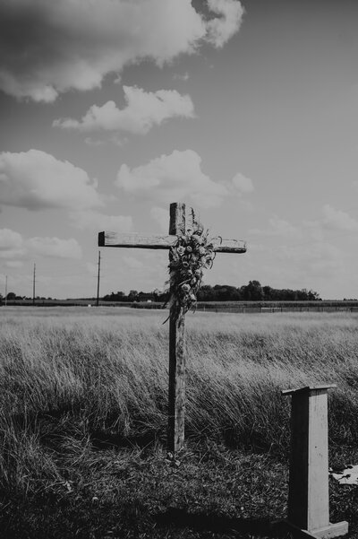 wooden cross with flowers standing in a field