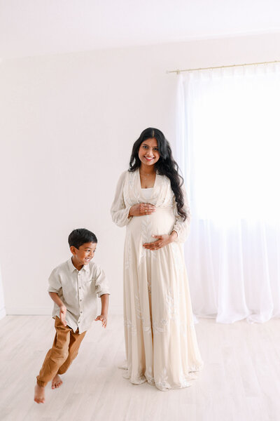 Elegantes Babybauchfoto im Negligee beim Schwangerschaftsshooting. Das Babybauchshooting ist stilvoll in hellen und zarten Tönen gehalten.