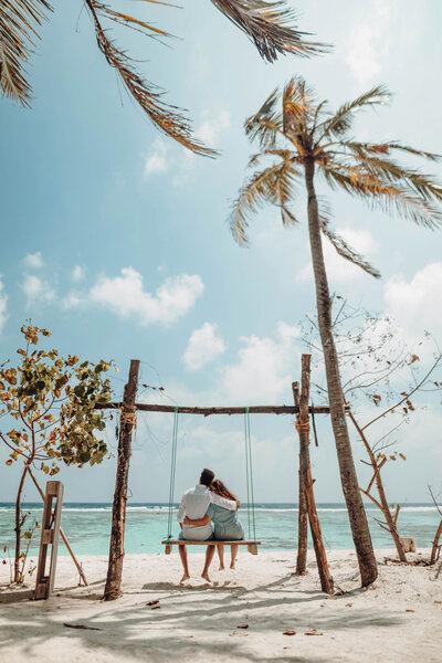 A couple enjoying the swings on the beach at their all-inclusive honeymoon