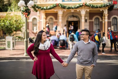 Newly engaged couple share a kiss at Disneyland hiding behind their Just Engaged Disneyland buttons