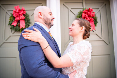 Bride and Groom embrace in front of green doors in winter themed wedding in northern Virginia