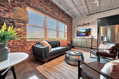 Living room with exposed brick in this one-bedroom, one-bathroom luxury condo in the historic Behrens building in downtown Waco, TX.