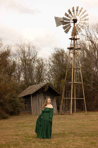 senior-girl-holding-green-dress-out-in-field-by-windmill