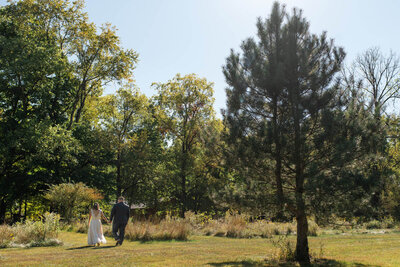 Bride and groom go for a quiet walk in a meadow on their wedding day