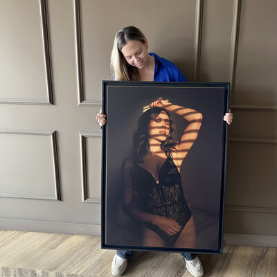 Juliette toont lachend een boudoir kunstwerk in Studio Laurant