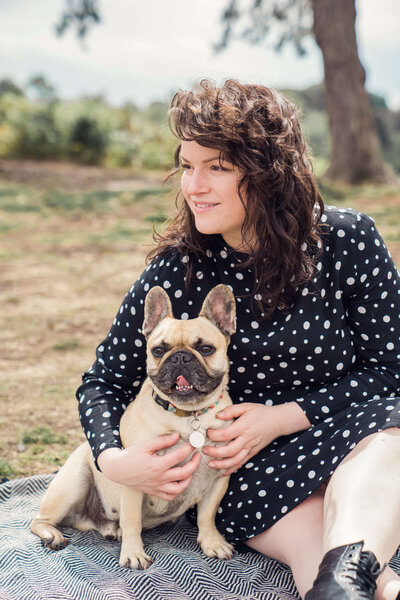 Laura and her dog sit in a field and look away from the camera while having personal brand photograph shoot