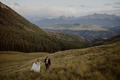 Couple walks up a hill with Telluride Mountains in the background