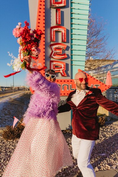 Bride and groom dancing in front of a retro diner in Denver on their colorful Valentine's Day elopement