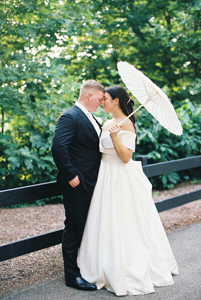 married couple holding a parasol snuggling 