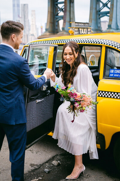 A bride steps out of  vintage NYC taxi during her wedding