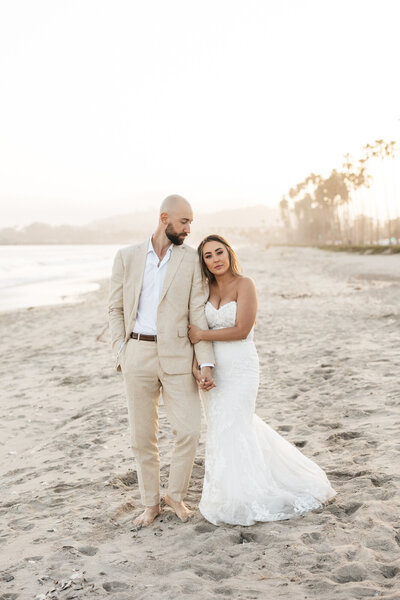 Bride and groom holding hands on beach at sunset at Hilton Beachfront Resort Santa Barbara in California