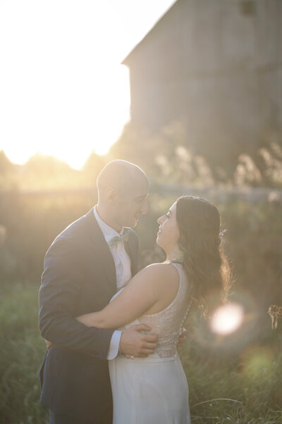 Les nouveaux mariés se retrouvent dans les bras l’un de l’autre sous la lumière dorée du golden hour, lors d’un mariage rustique et champêtre sous chapiteau en Montérégie, célébré avec authenticité sur la terre familiale