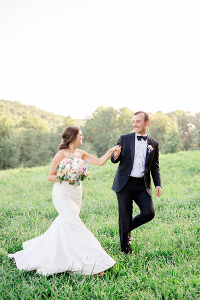 bride and groom walking through field