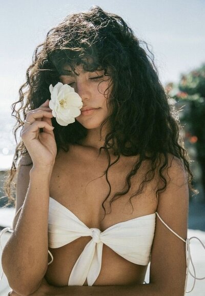 Woman with a flower near her face, embodying deep healing and compassionate self-connection.