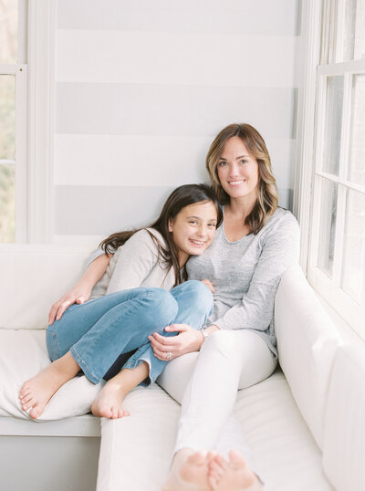 Mother and daughter sitting on a window seat