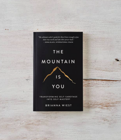 The Mountain Is You book sitting on a white wood background