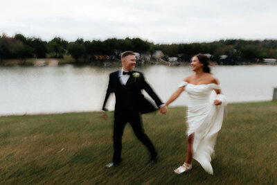bride and groom run next to lake on wedding day