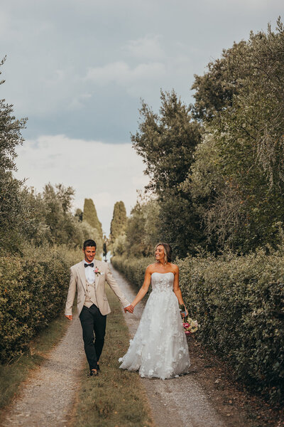 bride and groom hold hands whilst walking in Tuscany