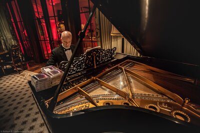 man in tux plays piano at evening cocktail party