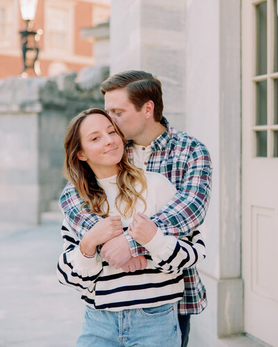 A newly engaged couple kisses while hugging.
