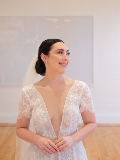 Bride in lace gown smiles radiantly in soft natural light