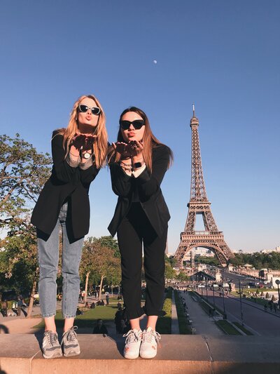 Two women posing blowing kisses near the Eiffel Tower Paris, France