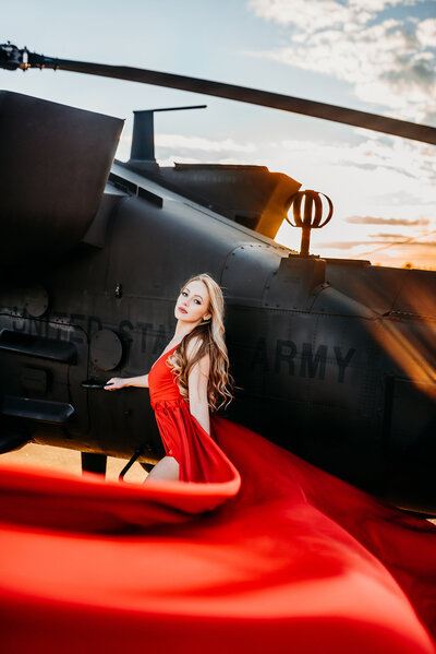 a model close up in front of a helicopter with her gown flowing in the wind