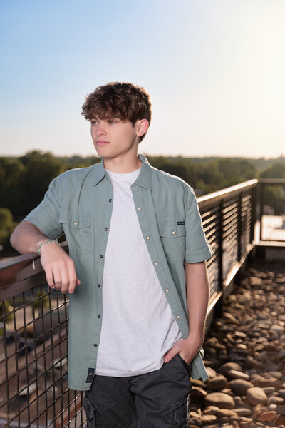 High School Senior leaning against a railing looking at the Raleigh skyline..