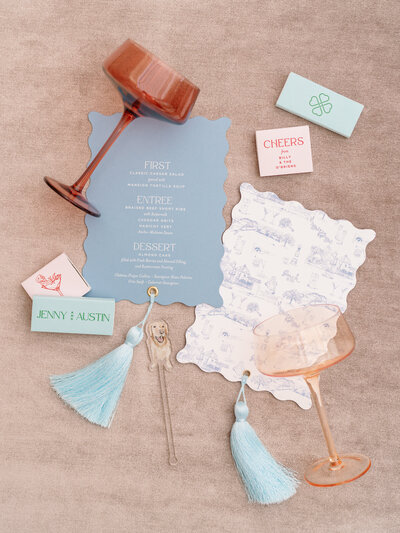 Detail of a wedding ring in a sage green box, next to green and white wedding invitations for an NYC wedding