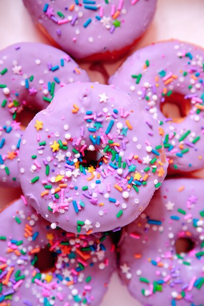 a pile of donuts with light purple frosting and rainbow sprinkles for reels and tiktok editing  socialfizz