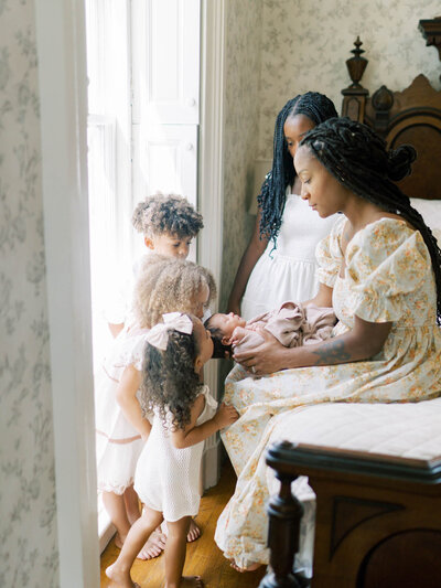 Mom in white dress holding newborn in front of a white fence on film by richmond newborn photographer