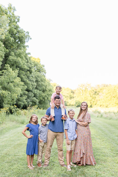 Whole family together in blues and pinks and smiling at the camera at Phillips Park in Beavercreek, Ohio.