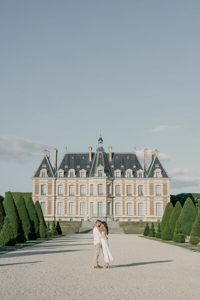 couple poses for engagement session with Chateau Du Sceaux as their background