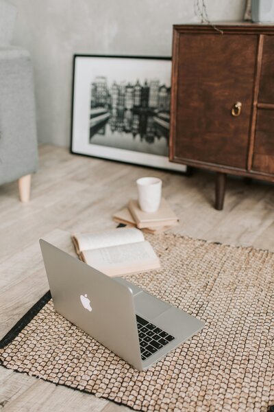 Macbook sitting on the floor next to a book and coffee