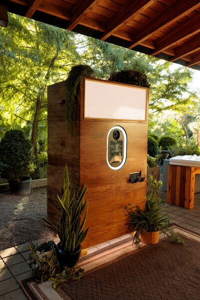 upscale sleek and inviting photo booth in a wooden enclosure surrounded by plants