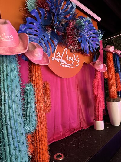 Custom Austin corporate event planning backdrop for LaCroix with vibrant florals, painted cacti, and branded styling elements.