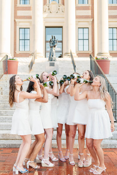 Group of 9 grads drinking champagne and celebrating graduation at Assumption University taken by best college grad photographer in Worcester, MA
