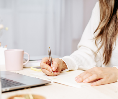 Photo of a notebook and pen next to a keyboard.
