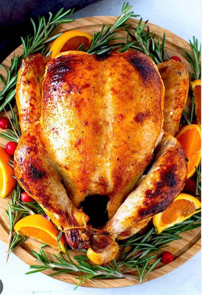 Roasted whole free-range chicken from Lost Shoe Ranch, served on a wooden platter with fresh rosemary and orange slices.
