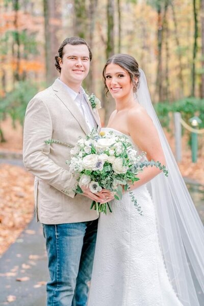 man in sports coat hugging girl in white dress with veil and flowers while smiling