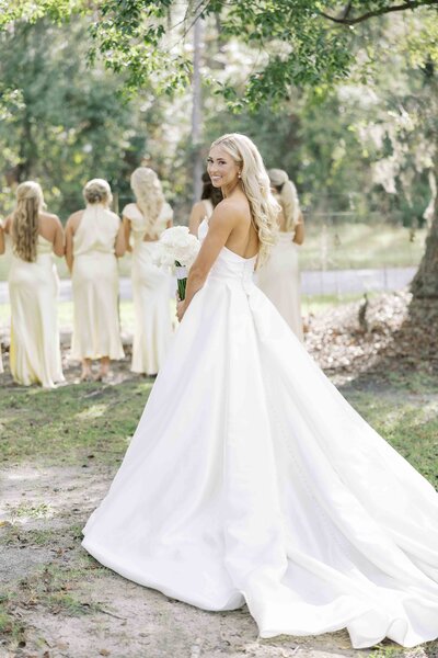 a bride walking to surprise her bridesmaids with her wedding dress