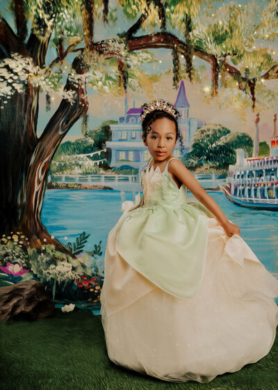 A bayou scene with a girl wearing a green and yellow  tiana inspired gown twirling around