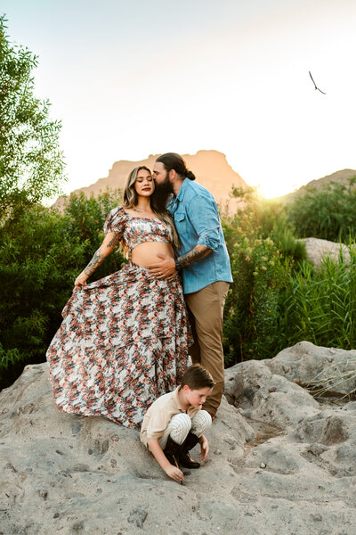 Maternity mom and family standing on rock.