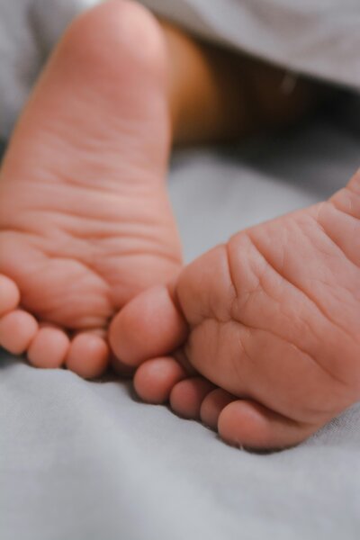 Close-up of tiny baby feet against a soft blanket, symbolizing the tenderness of new beginnings and postpartum care.